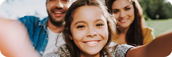 Young girl taking a smiling selfie with her parents